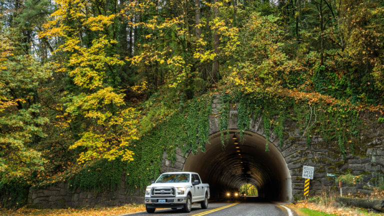 Vehicles drive through a stone tunnel leading to the entrance of Forest Park, the largest park in Portland, Oregon.