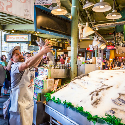 Customers at Pike Place Fish Company in Seattle, Washington. This market, opened in 1930, is known for their open air fish market style.