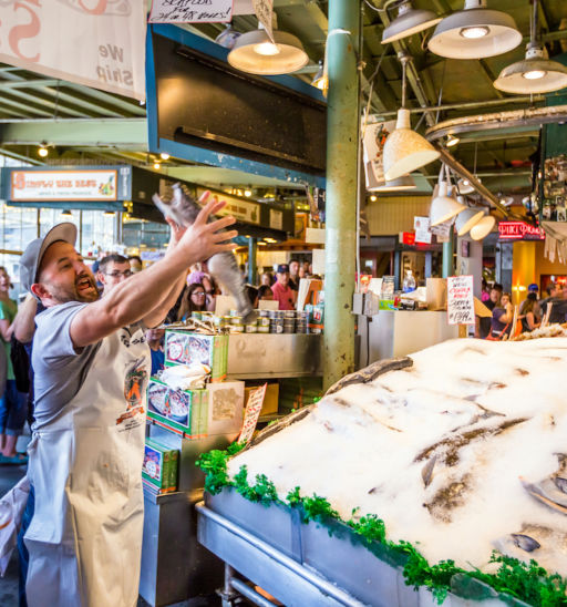 Customers at Pike Place Fish Company in Seattle, Washington. This market, opened in 1930, is known for their open air fish market style.
