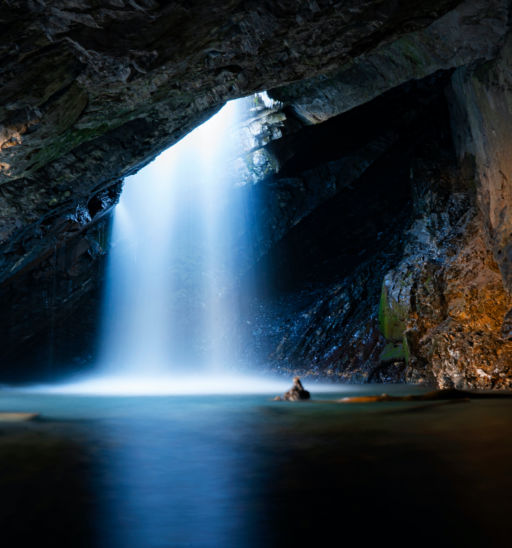 Beautiful shot of a stunning waterfall dropping down from a hole inside of a cave on a cold autumn day in Big Cottonwood Canyon located in Utah.