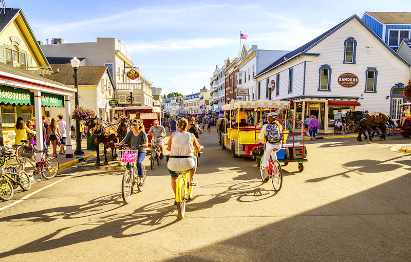 Mackinac Island, Michigan, August 8, 2016: Vacationers take on Market Street on Mackinac Island that is lined with shops and restaurants. No motorized vehicles are allowed on the island. Photo via Shutterstock.