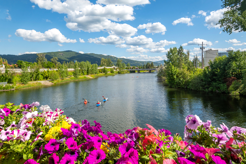 Greatest Summertime Lake Towns: A group of kayakers enjoy a beautiful summer day on Sand Creek River and Lake Pend Oreille 
in the downtown area of Sandpoint, Idaho. Photo via Shutterstock.