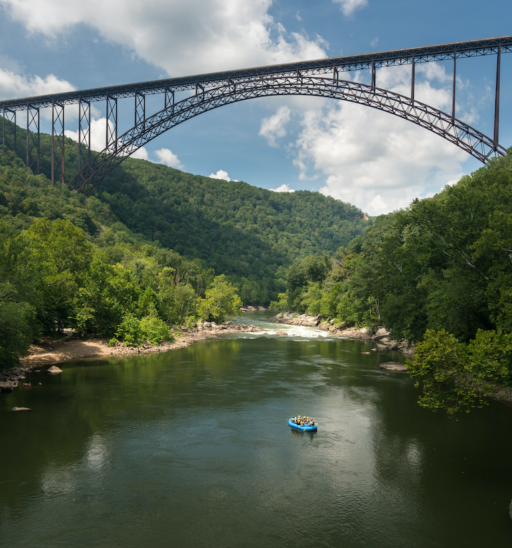 Rafters float towards the rapids under the high arched New River Gorge bridge in West Virginia