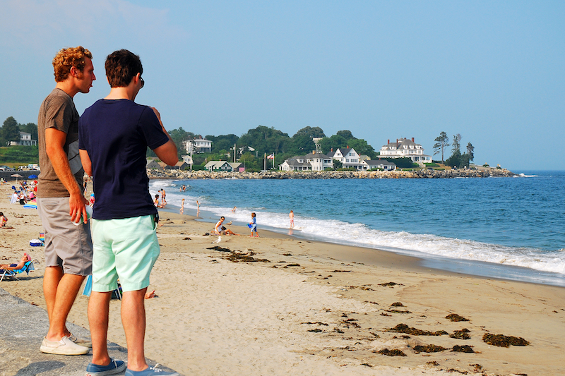 Rye, NH, USA July 15 Two young men taken in the ocean view along a seawall at Jenness Beach State Park in  Rye, New Hampshire. Photo by Shutterstock.