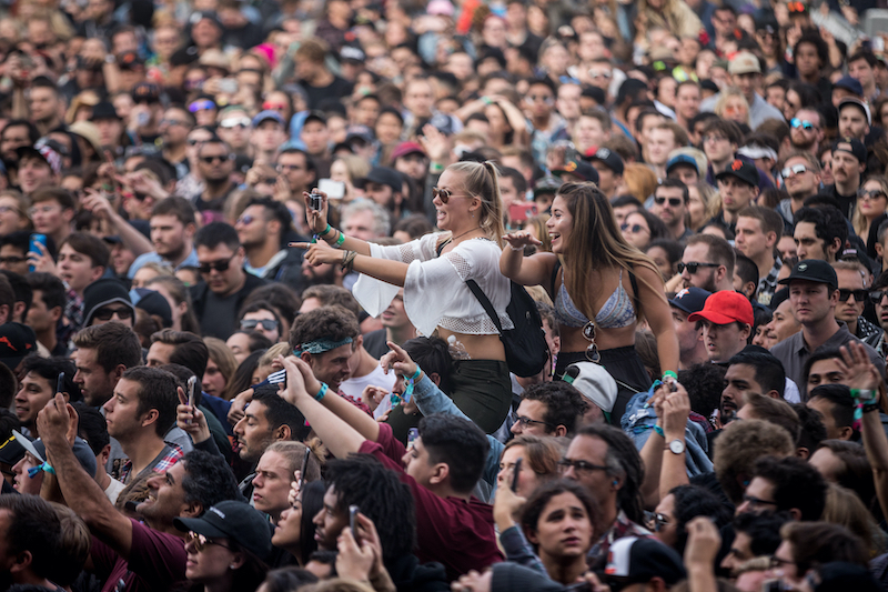 SAN FRANCISCO, CA - AUGUST 12, 2017: Women on man's shoulders shooting a selfie among fans  watching the band Cage The Elephant at the Lands End stage at the Outside Lands Music Festival at Golden Gate Park. Photo via Shutterstock.