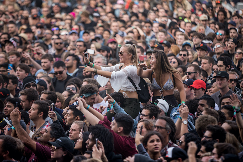 SAN FRANCISCO, CA - AUGUST 12, 2017: Women on man's shoulders shooting a selfie among fans watching the band Cage The Elephant at the Lands End stage at the Outside Lands Music Festival at Golden Gate Park. Photo via Shutterstock.
