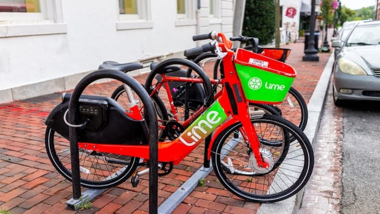 Washington DC - August 18, 2021: M street parking bicycle rack for Lime bike bicycle sign on historic street red brick buildings in Georgetown. Photo via Shutterstock.