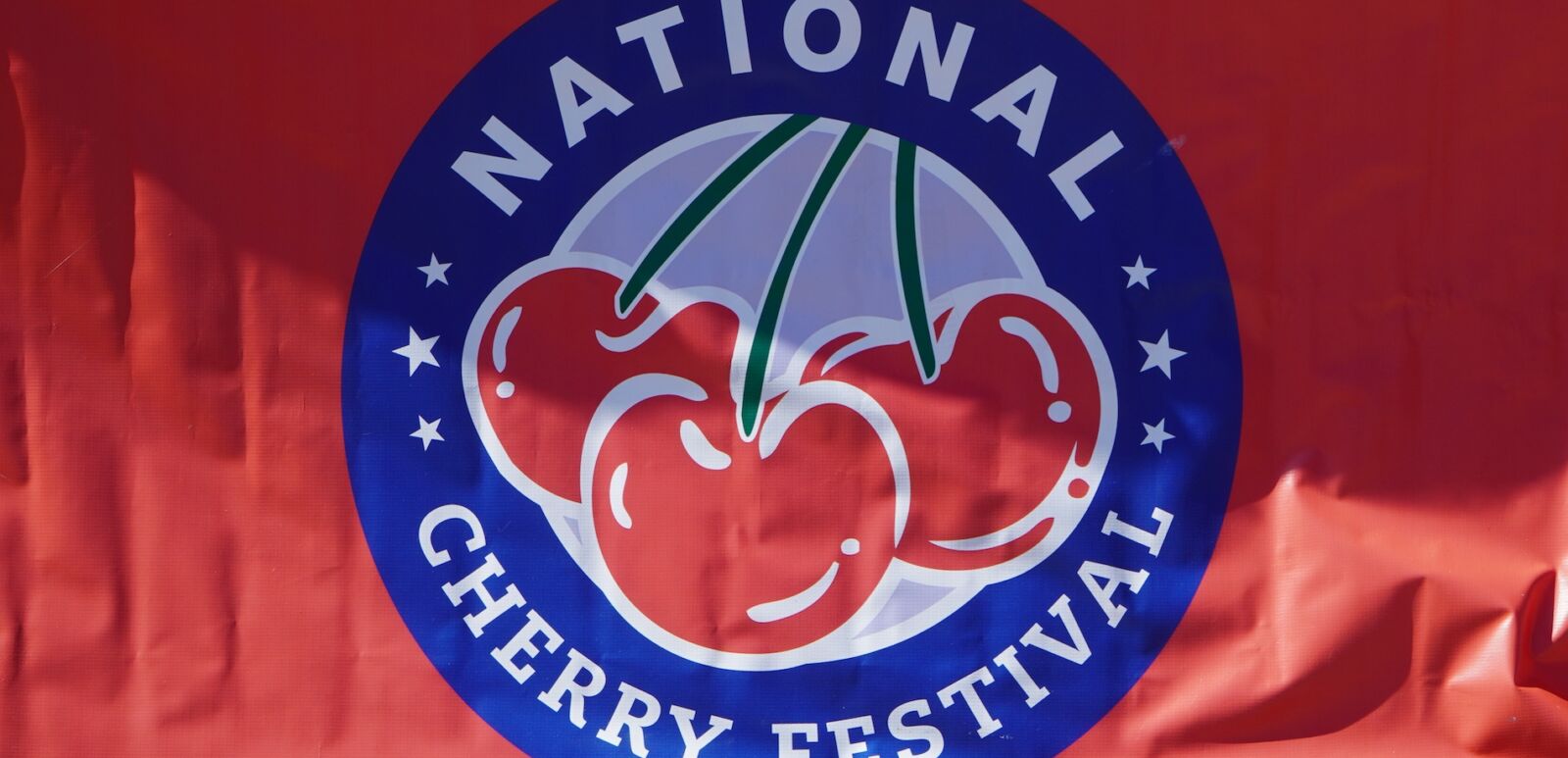 Logo for the National Cherry Festival in Grand Traverse City hanging over a barricade. Photo via Shutterstock.