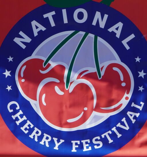 Logo for the National Cherry Festival in Grand Traverse City hanging over a barricade. Photo via Shutterstock.