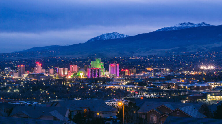 View of downtown Reno, NV at dusk with the Sierra Nevada Mountains in the background. Photo by Shutterstock.