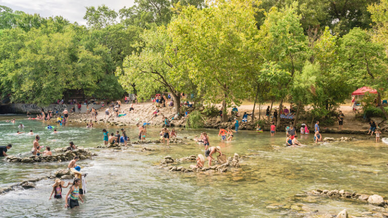 Best places for solo travel: Austin, Texas. August 13, 2016: Unidentified people swimming and enjoy cold natural water at Barton Creek. Photo via Shutterstock.