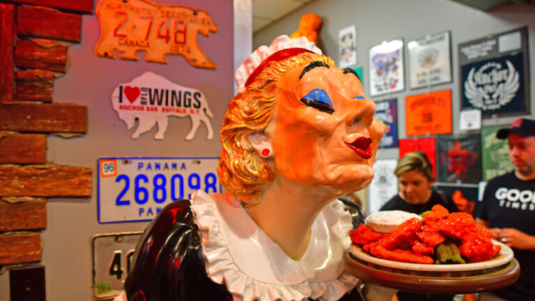 Best places for solo travel: Buffalo. Buffalo, NY, July 4, 2019 - Statue of a waitress holding a plate of hot wings at the iconic Anchor Bar in Buffalo. Photo via Shutterstock.