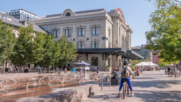 Best places for solo travel: Denver, Colorado. August 28, 2021: A person rides a bicycle in the plaza at Union Station, downtown, in the LoDo (Lower Downtown) neighborhood. Photo via Shutterstock.