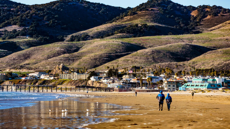 Pismo Beach, California, February 15, 2018: View of cliffs, Pacific Ocean, business district, and Pismo Beach Pier. Photo via Shutterstock.