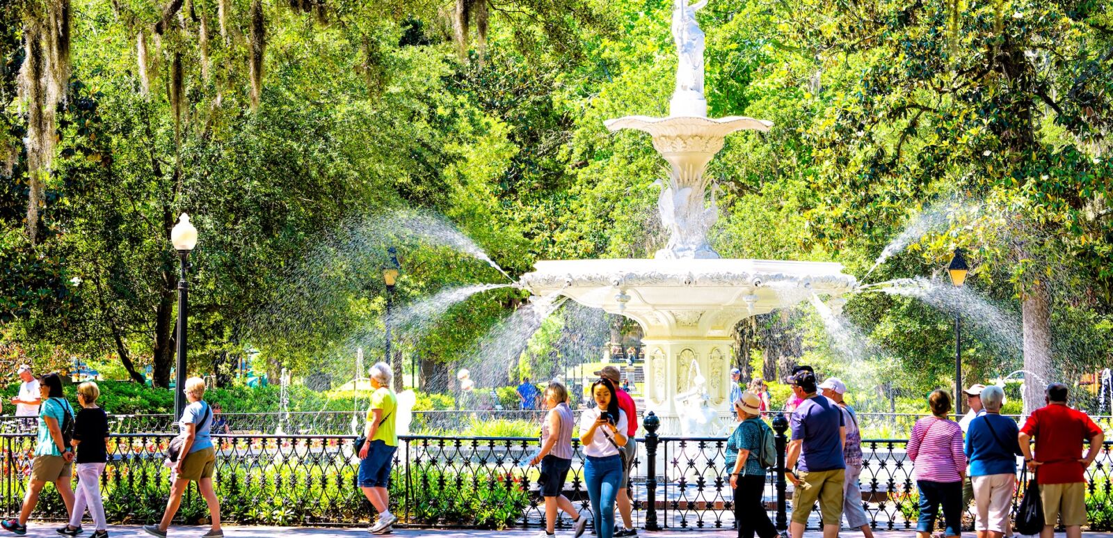 Savannah, Ga. Famous water fountain in Forsyth park, Georgia on sunny summer day with people walking by southern live oak with Spanish moss. Photo via Shutterstock.