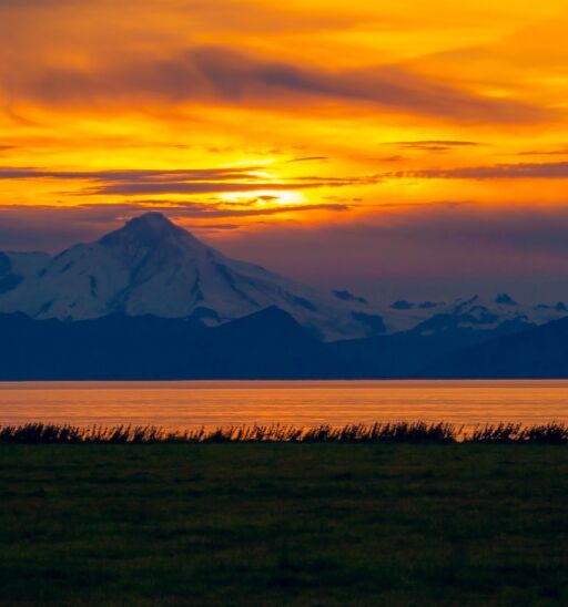 A solitary silhouette watches the sunset over Mount Iliamna in Ninilchik, Alaska. Photo by Shutterstock.