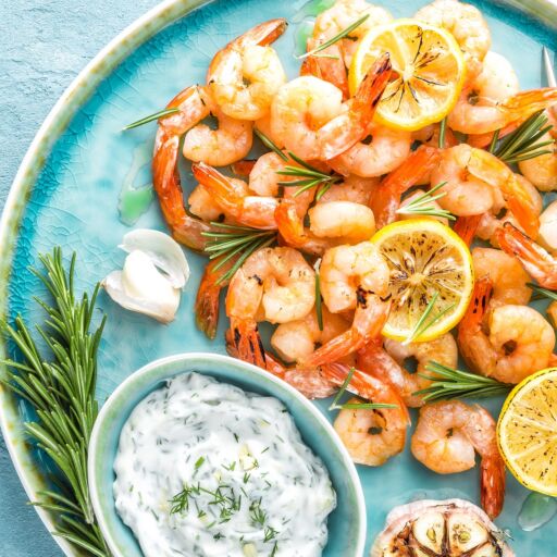 Grilled shrimps or prawns served with lemon, garlic and sauce. Seafood. Top view.