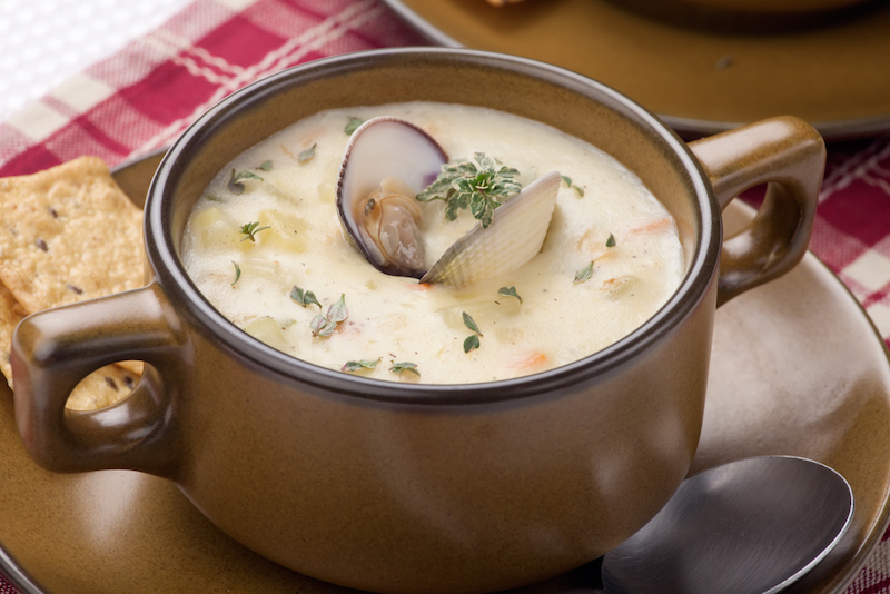 Bowls of hot delicious clam chowder garnished with fresh thyme, and multy grain crackers. Photo via Shutterstock.