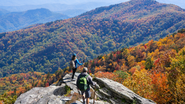 Couple hiking in the autumn mountains. Friends on top of the mountain enjoying beautiful autumn scenery. Blue Ridge Mountains, near Asheville, North Carolina, USA.