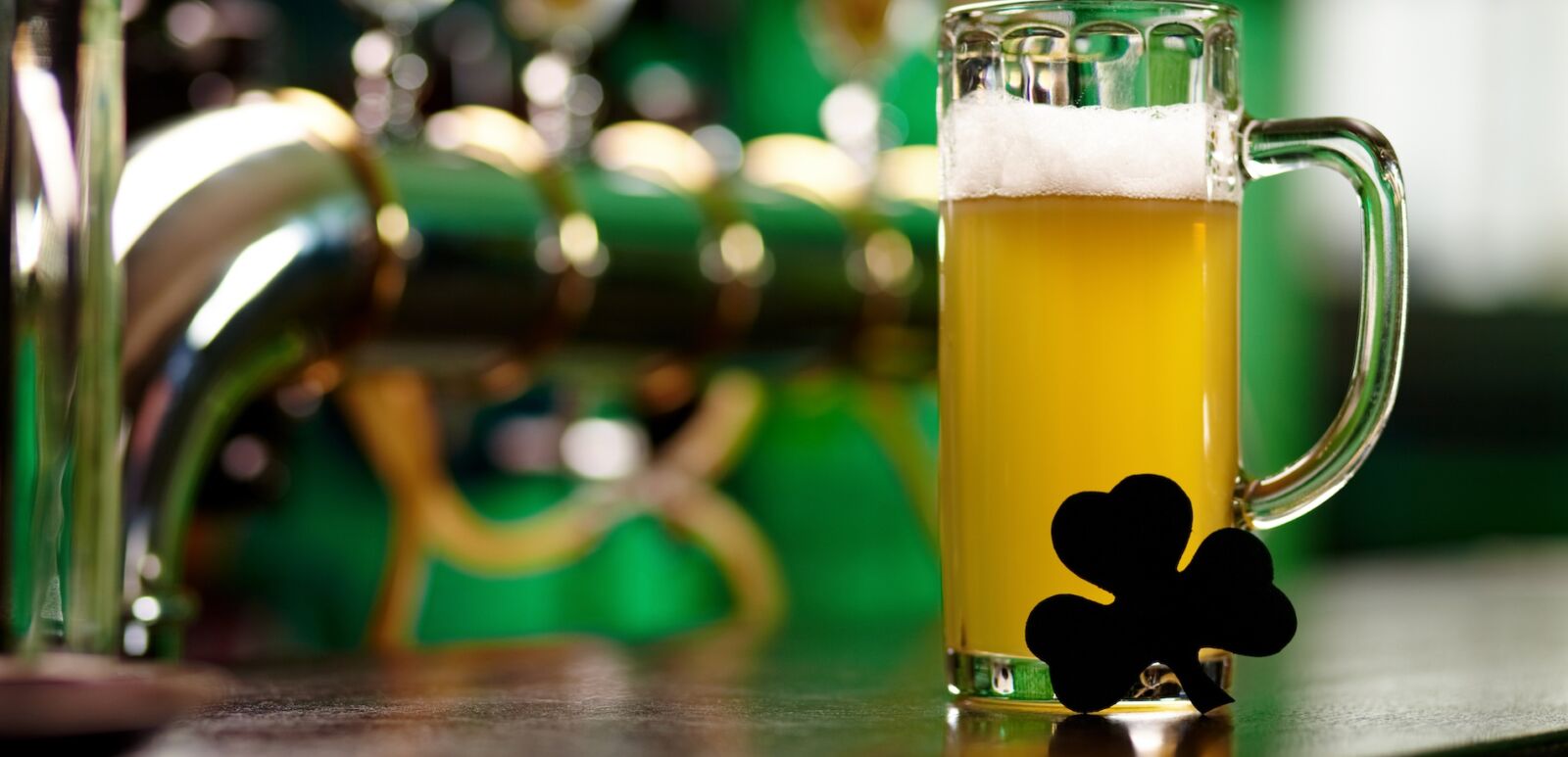 Image of glass of beer with shamrock leaf on pub table