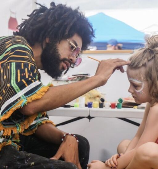 An artist paints a girl's face at Eclipse Utopiafest.