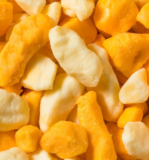 Raw organic yellow and white cheese curds in a bowl.